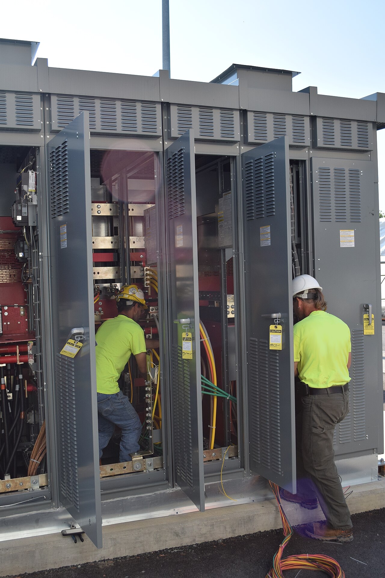 Electricians installing industrial electrical switchgear panels